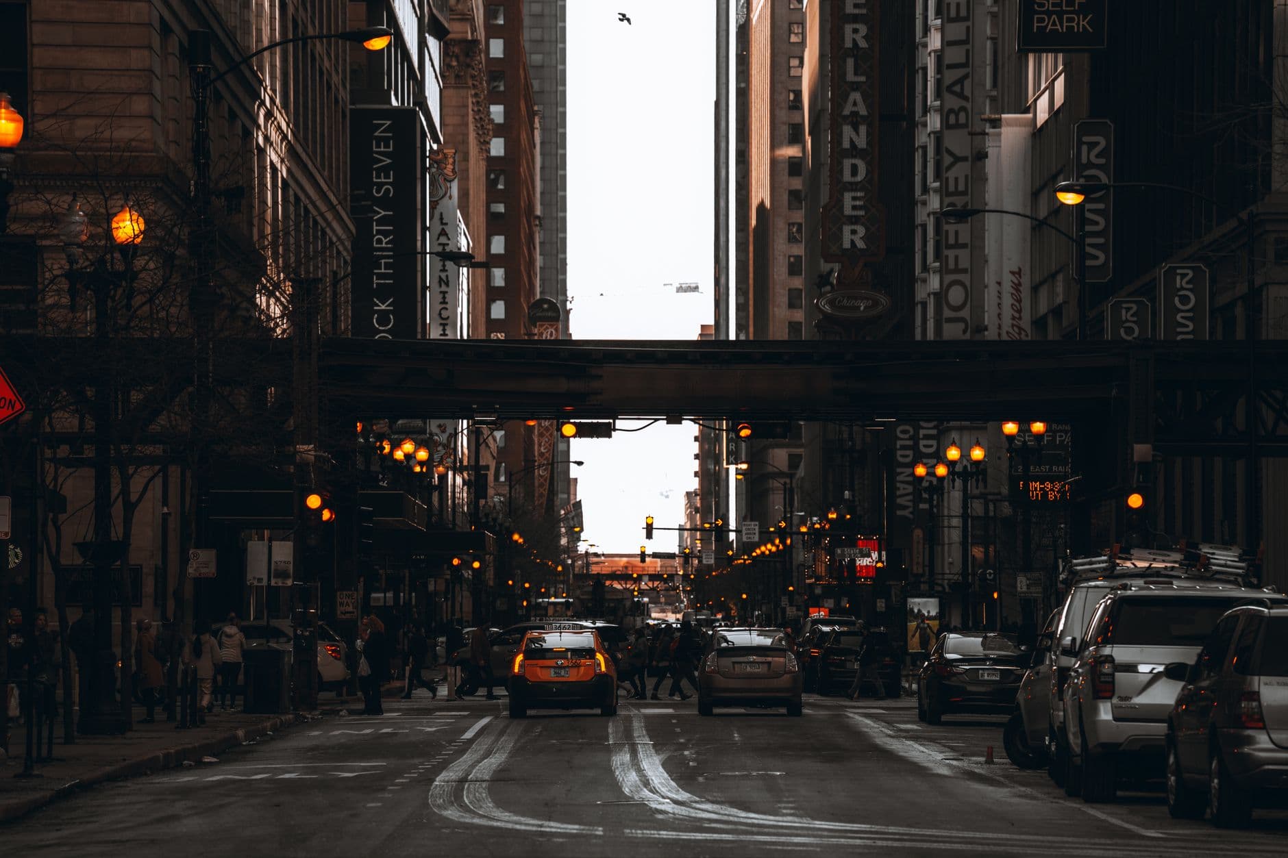 Vibrant street scene in downtown Chicago capturing cars, people, and illuminated city lights at dusk.