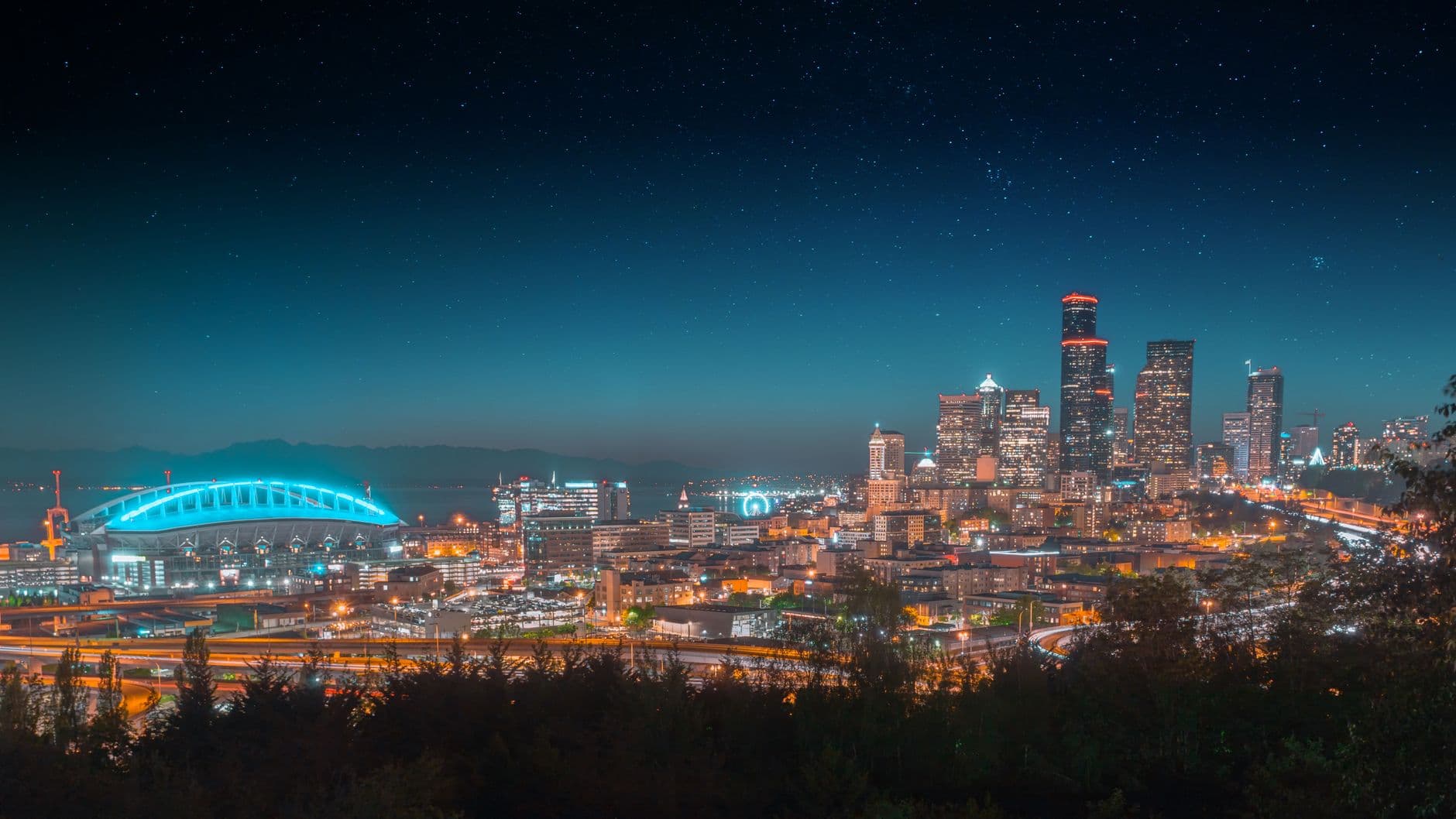 Beautiful night view of a city skyline with illuminated buildings and starry sky.