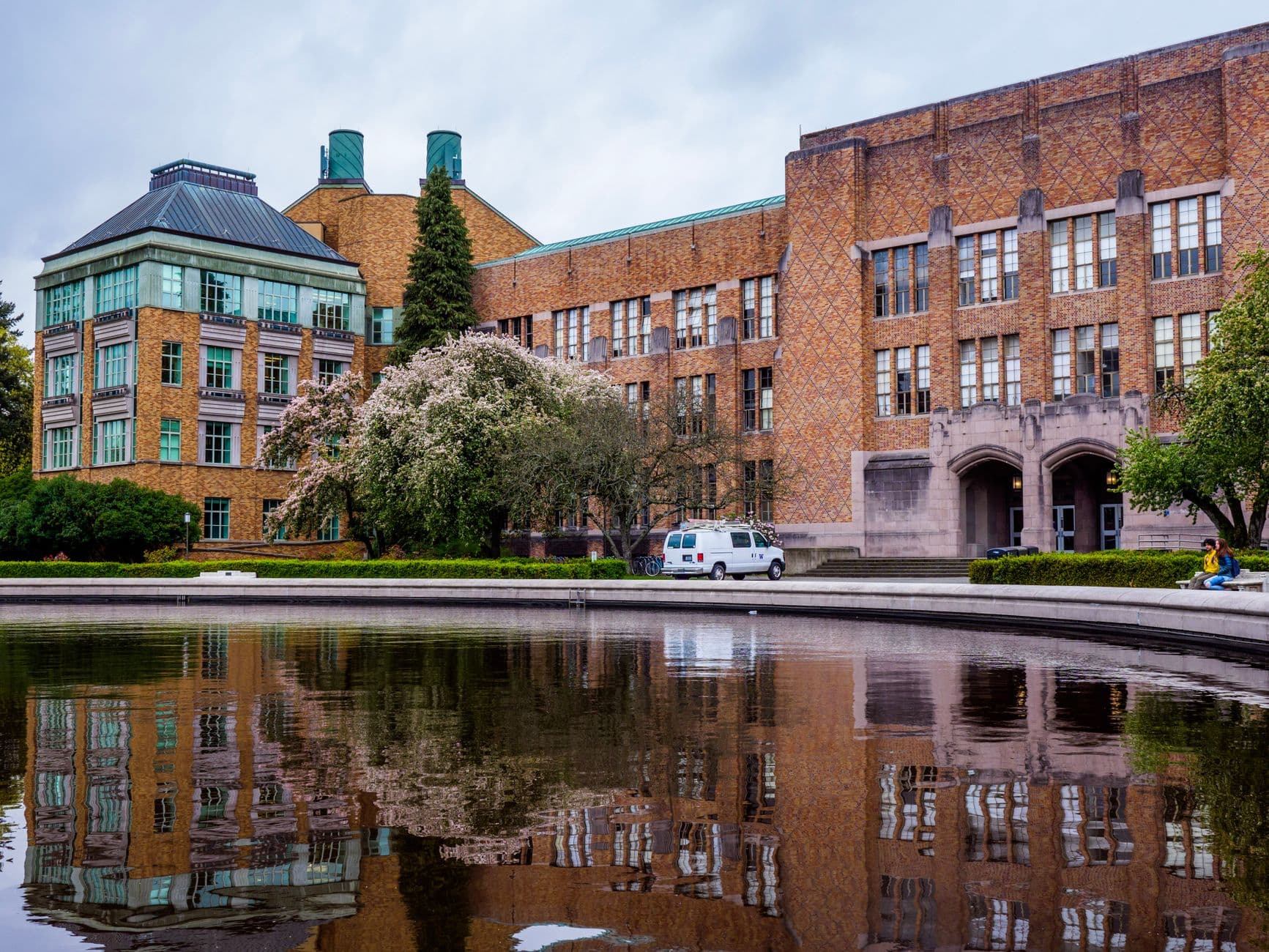 Serene university campus with classic architecture, reflecting in a tranquil pond.